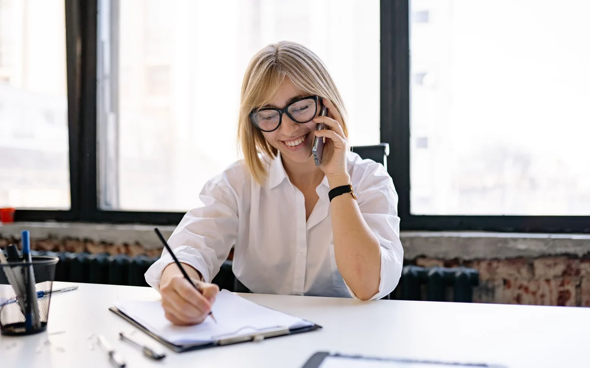 Persona de atención al cliente sonriendo con auriculares en una oficina